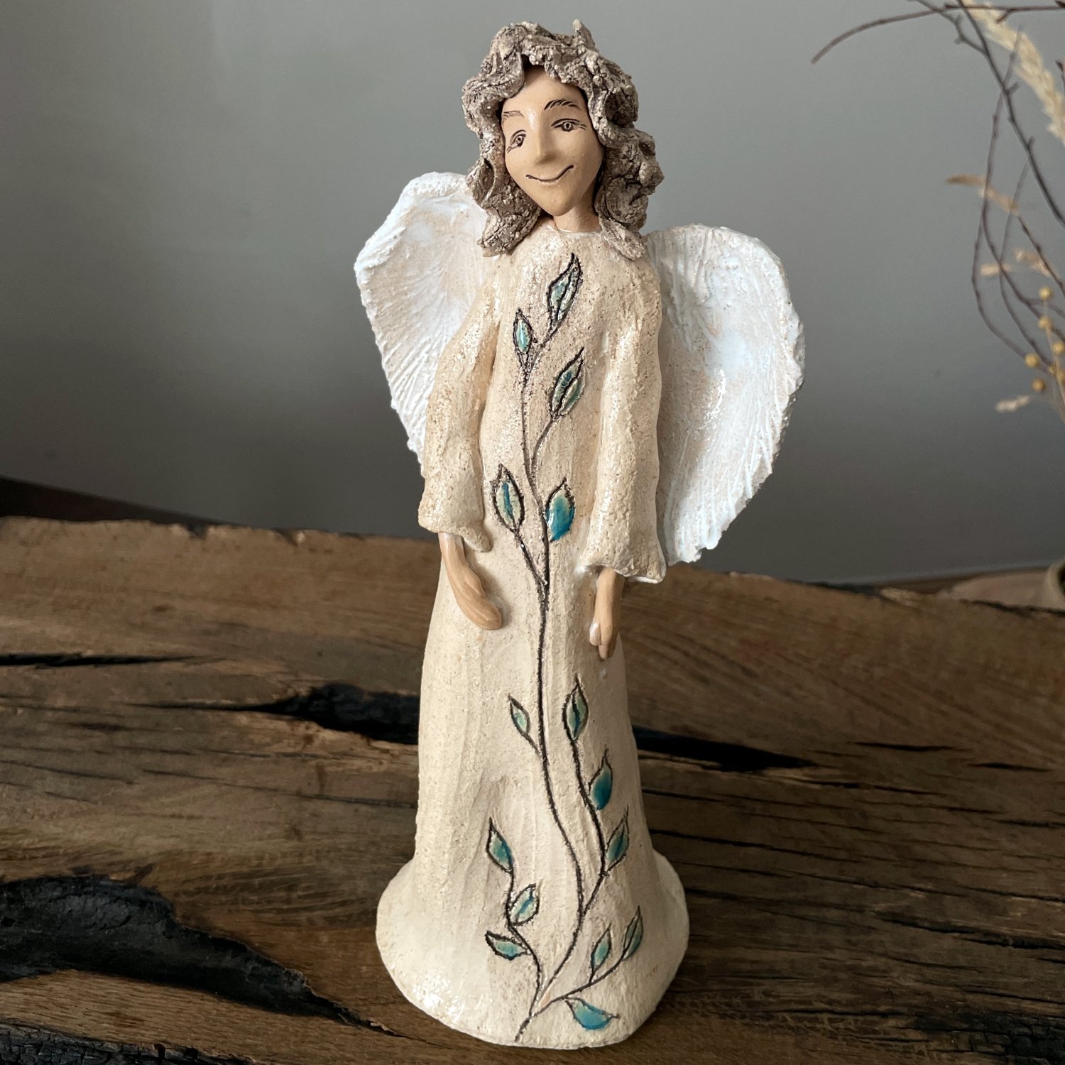 Handmade white angel figurine with textured wings and botanical decoration