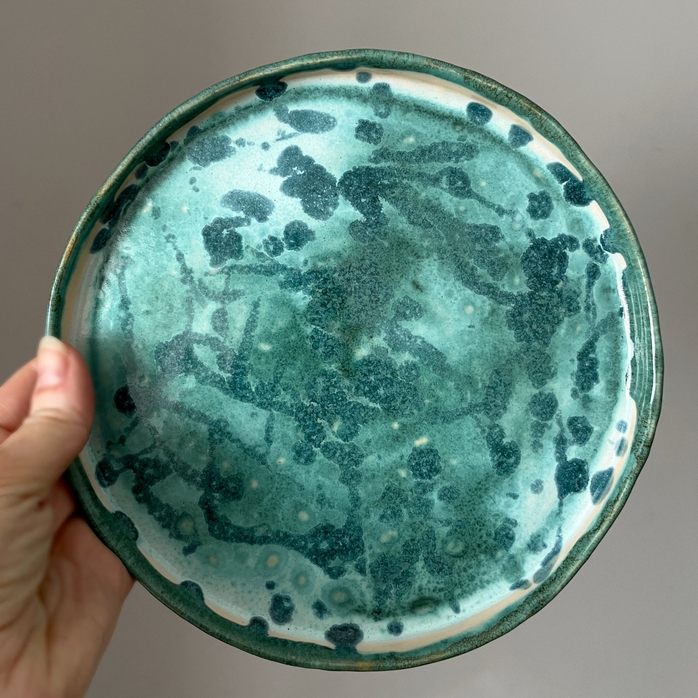 Round ceramic serving plate held in hand