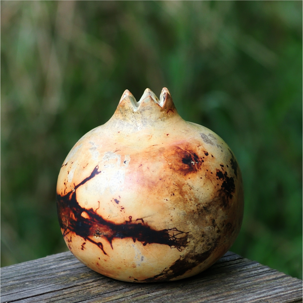 Handheld ceramic pomegranate vase showing saggar firing texture close‑up