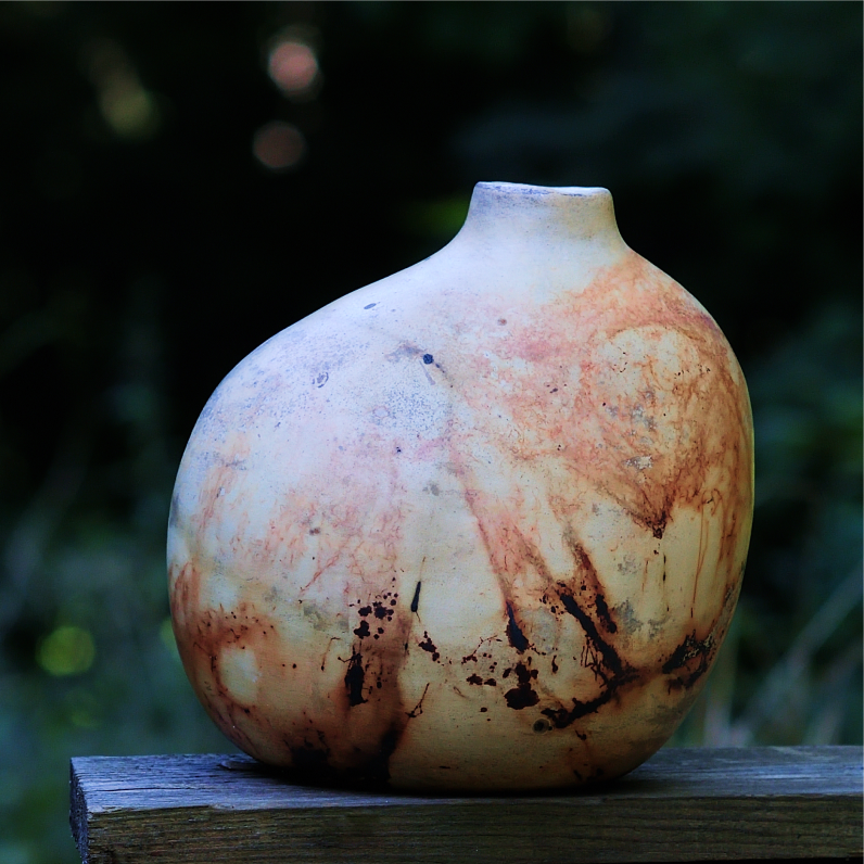 Close-up of handmade ceramic vase with asymmetrical shape and earthy natural textures.