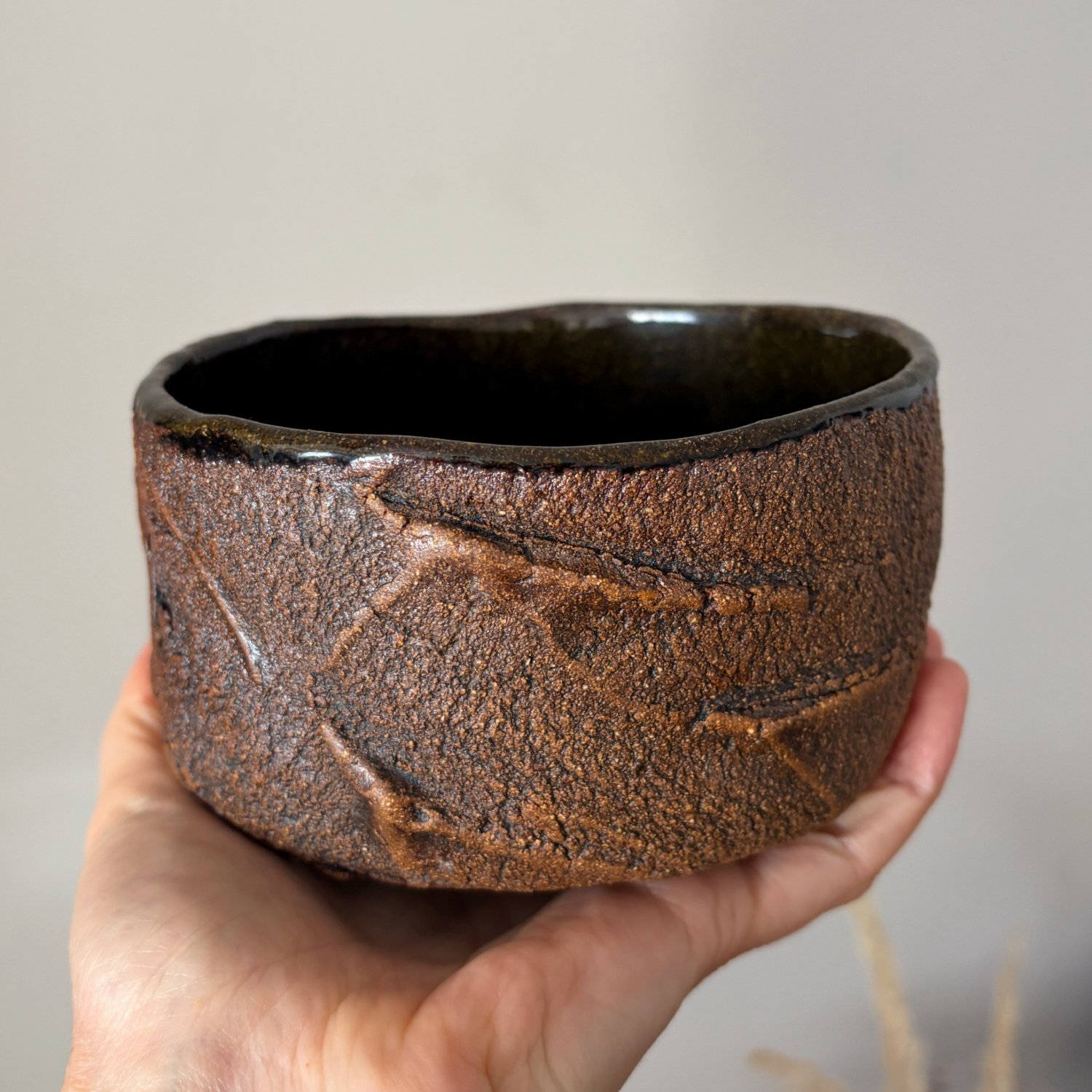 Handmade ceramic tea bowl held in hand for size reference