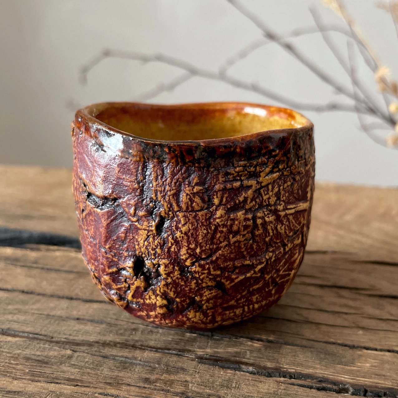 Side view of textured ceramic yunomi with earth-tone glaze