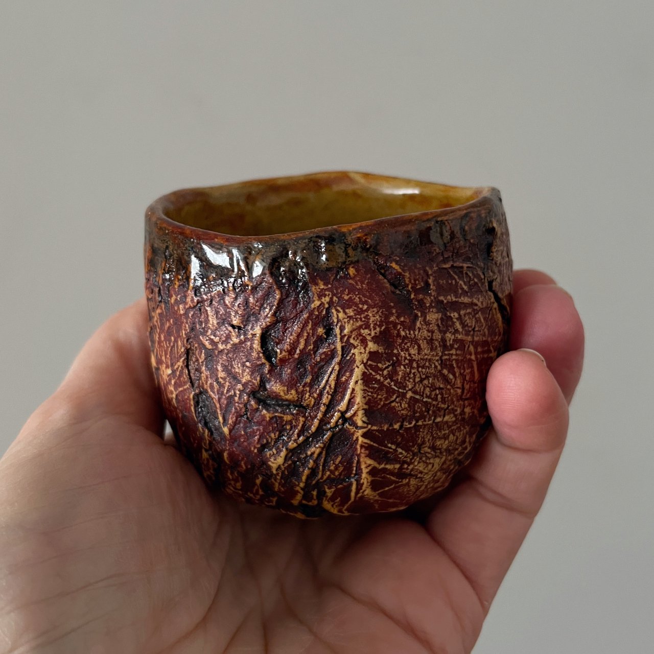 Handmade ceramic tea cup held in hand for size reference