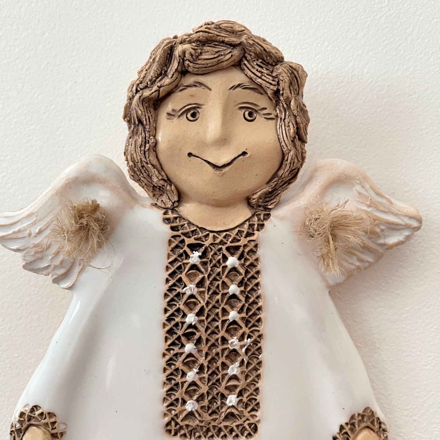 Close up of ceramic angel wall sculpture with white wings