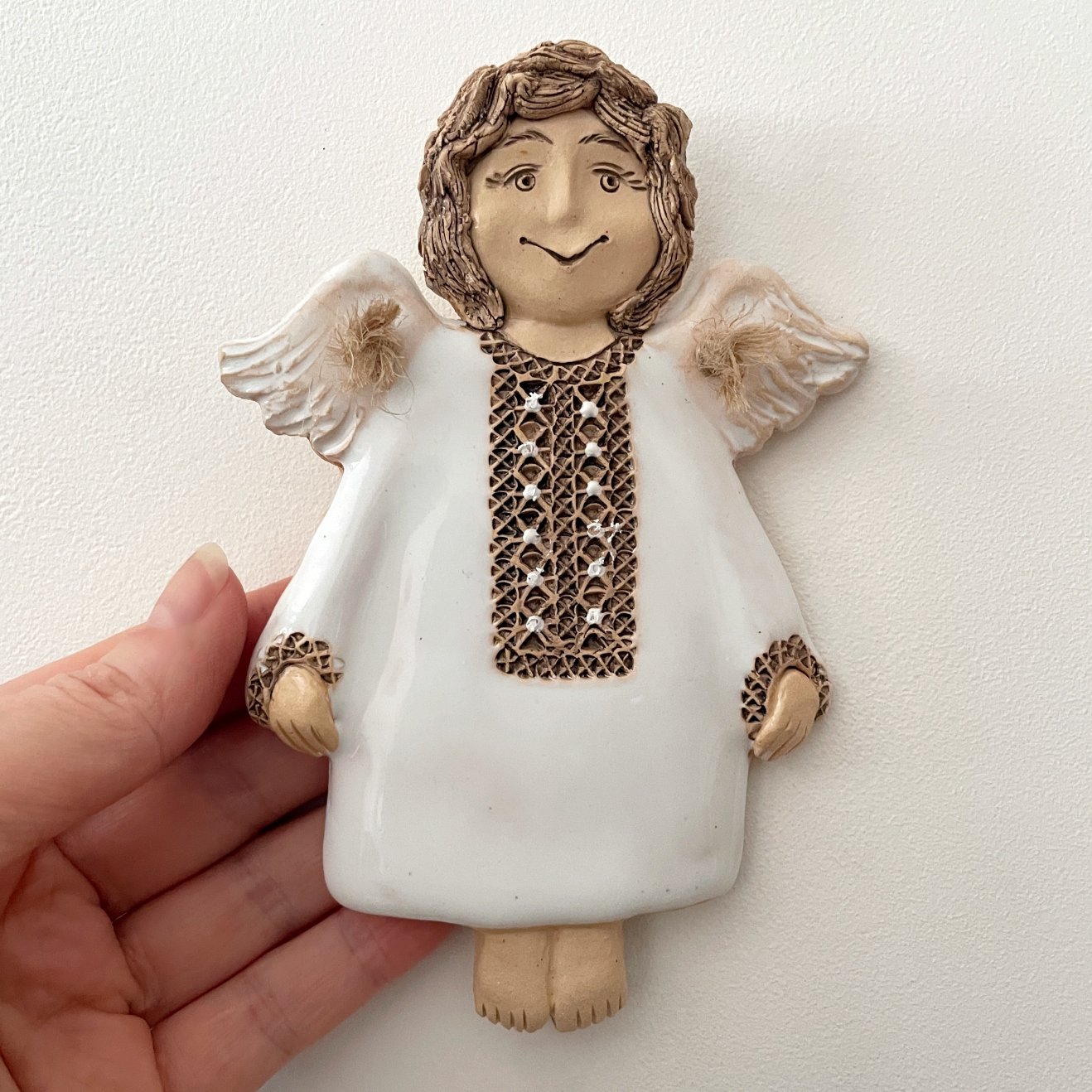 White ceramic angel wall decor held in hand