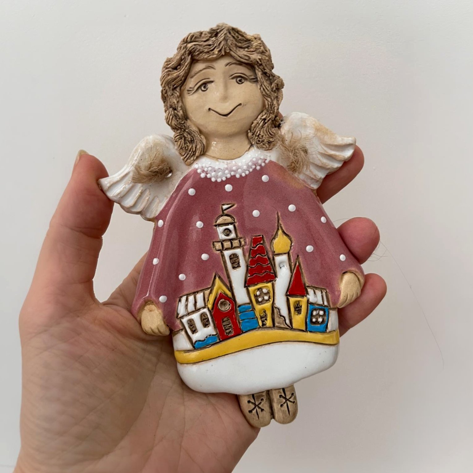 Handmade ceramic angel wall decor held in hand