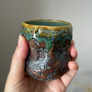Handmade ceramic espresso cup held in hand
