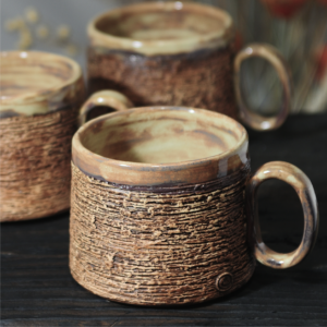 Handmade pottery mug with layered textured surface and handle