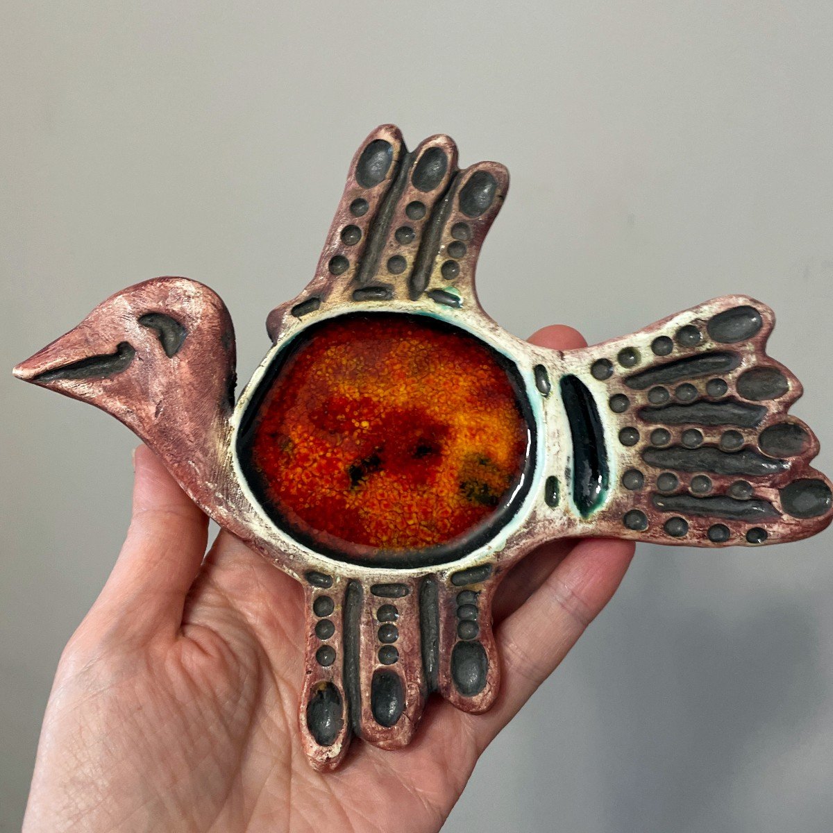Handmade ceramic bird wall decor with red glazed center and textured details