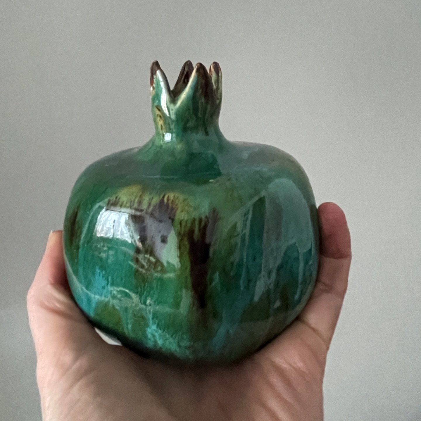 Green ceramic pomegranate sculpture held in hand