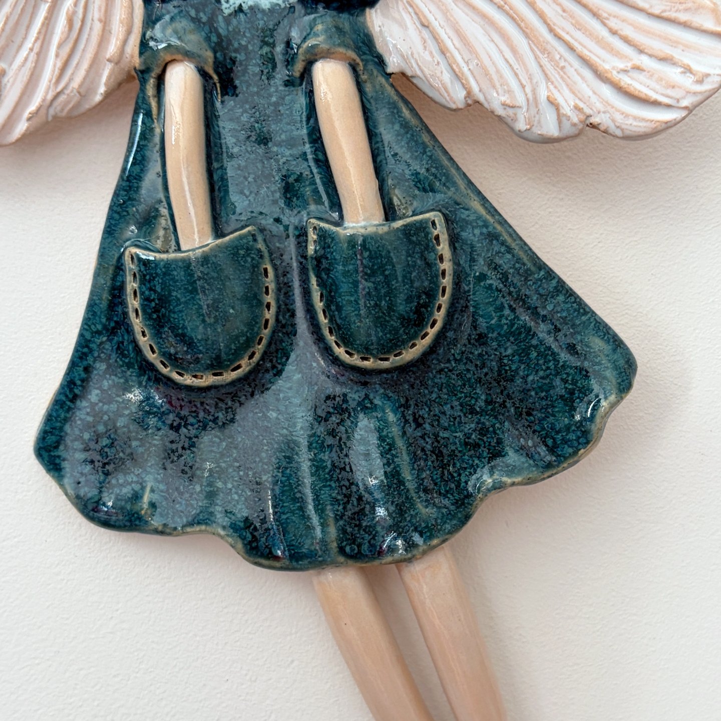 Close-up of teal dress on handmade ceramic angel