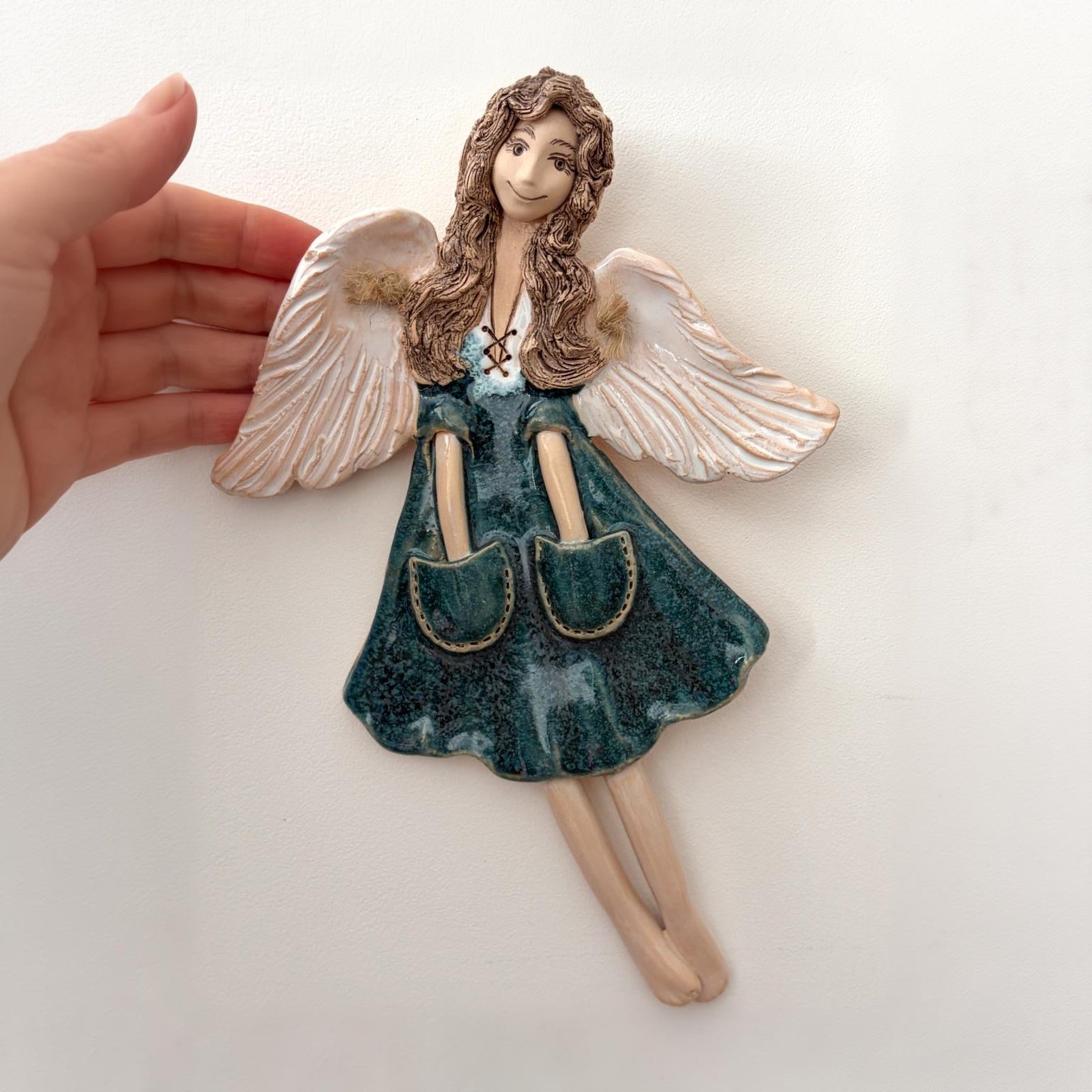 Ceramic angel wall decor held in hand, size reference