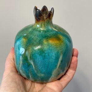 Front view of ceramic pomegranate vase held in hand
