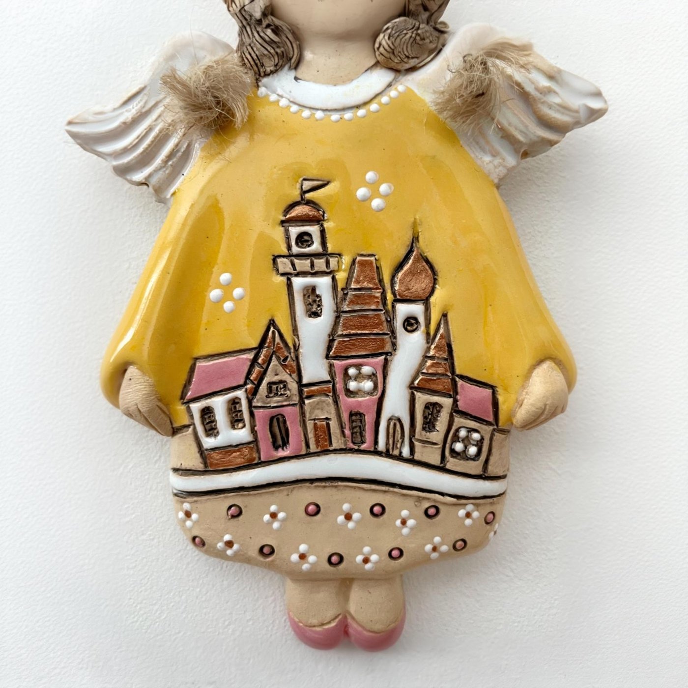 Close up of ceramic angel with hand painted village motif