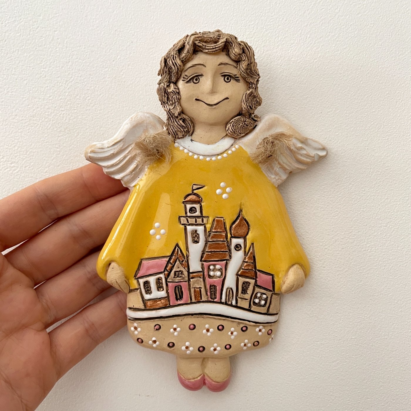 Handmade angel wall decor in yellow dress held in hand