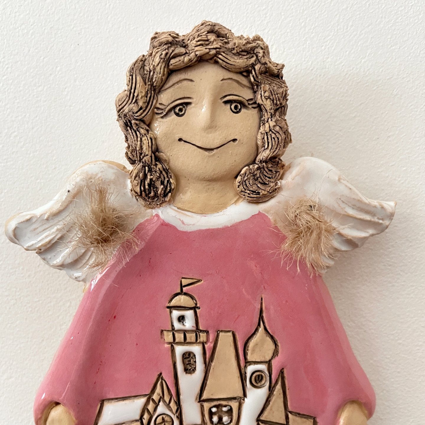 Ceramic angel plaque with village motif and white wings