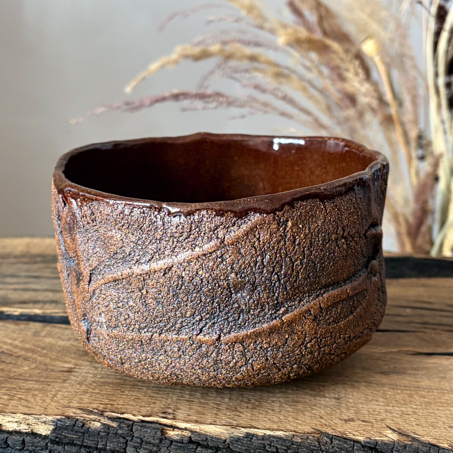 Handmade pottery bowl shown from the side with dark earthy glaze