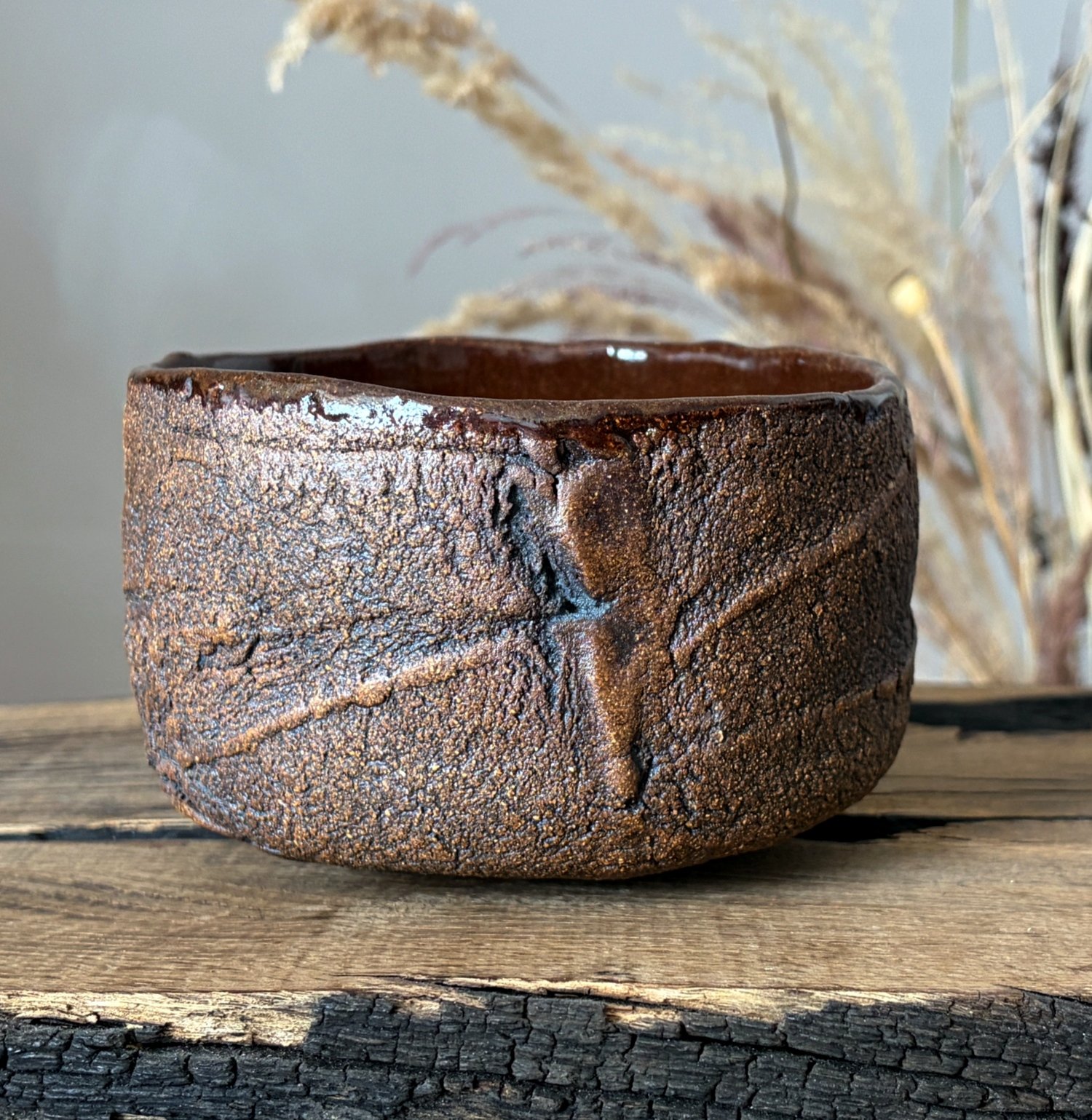 Artisan ceramic tea bowl with irregular textured surface and brown glaze