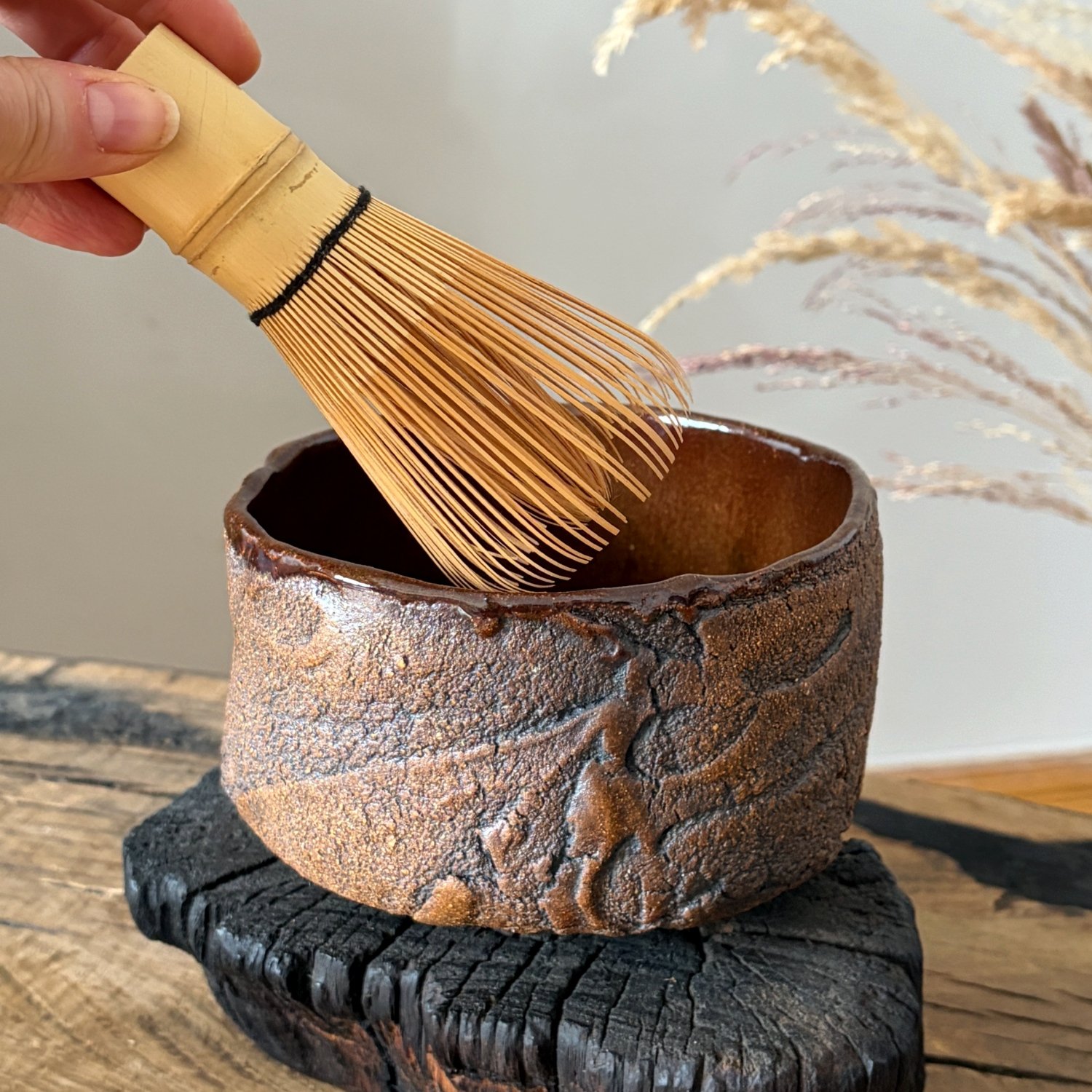 Ceramic matcha bowl with bamboo whisk and dark glazed interior