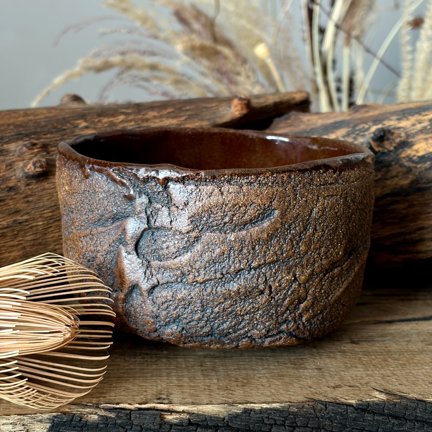 Handmade ceramic tea bowl with rustic brown textured exterior