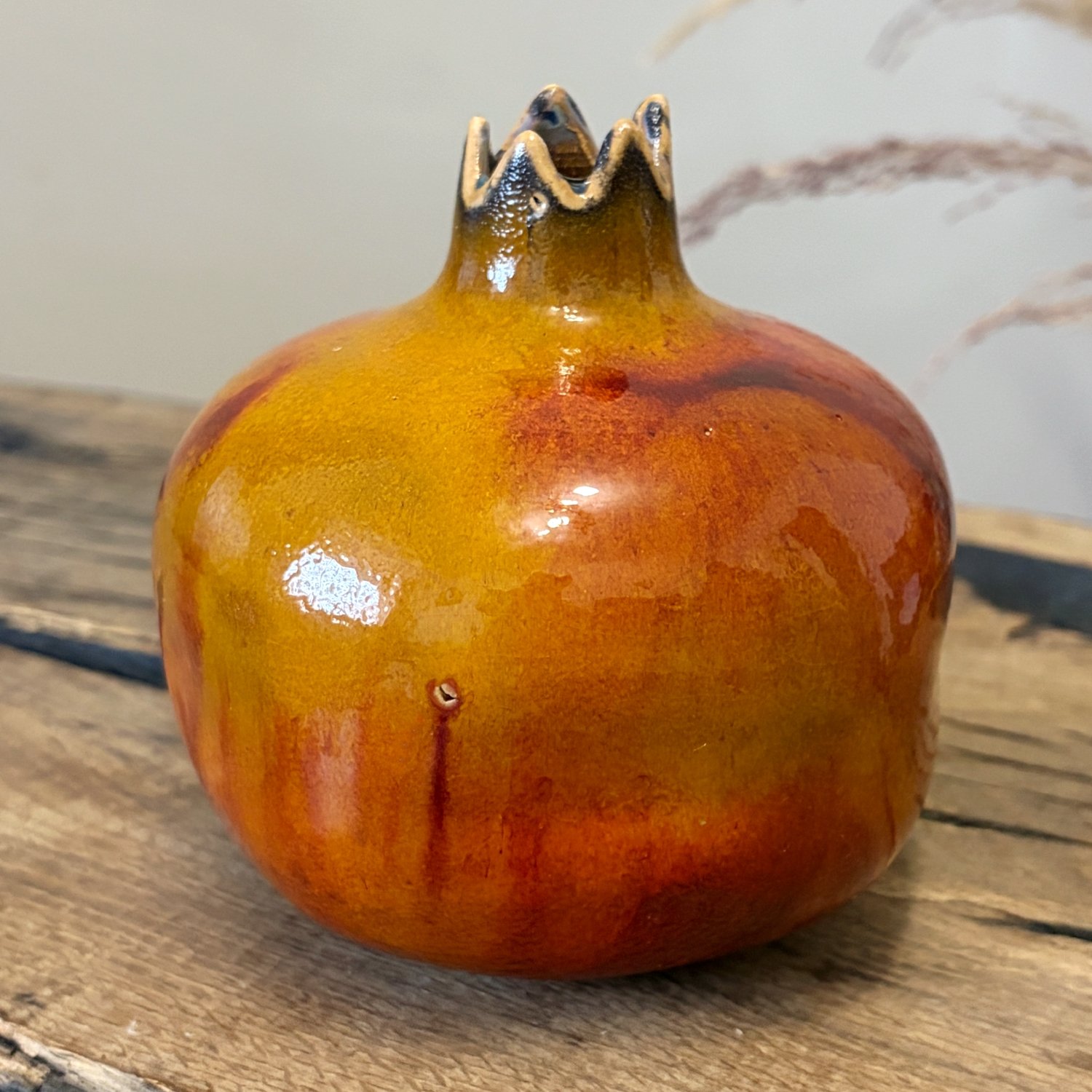Decorative ceramic pomegranate with flowing amber and red glaze