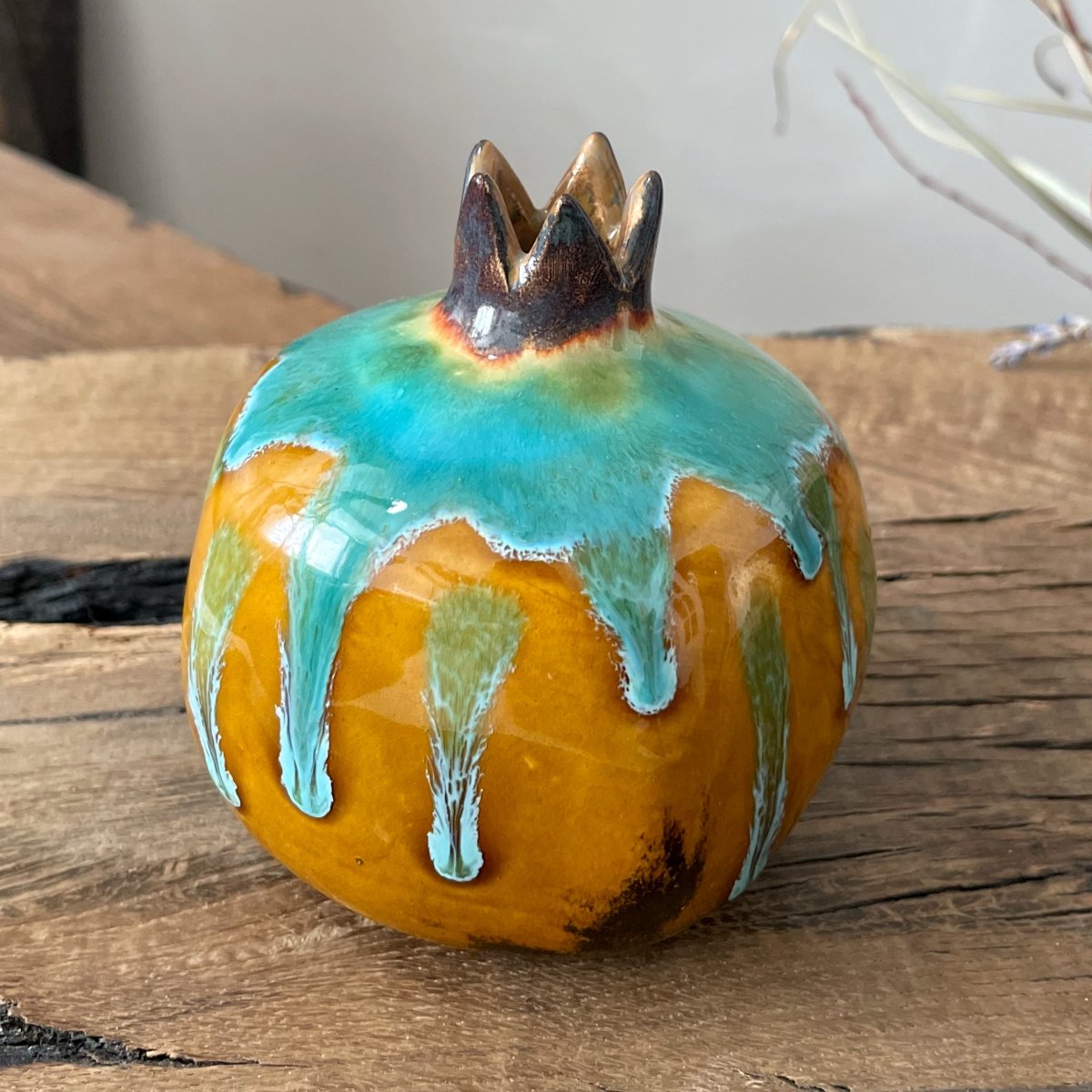 Small ceramic pomegranate in hand, pottery vase with organic glaze texture