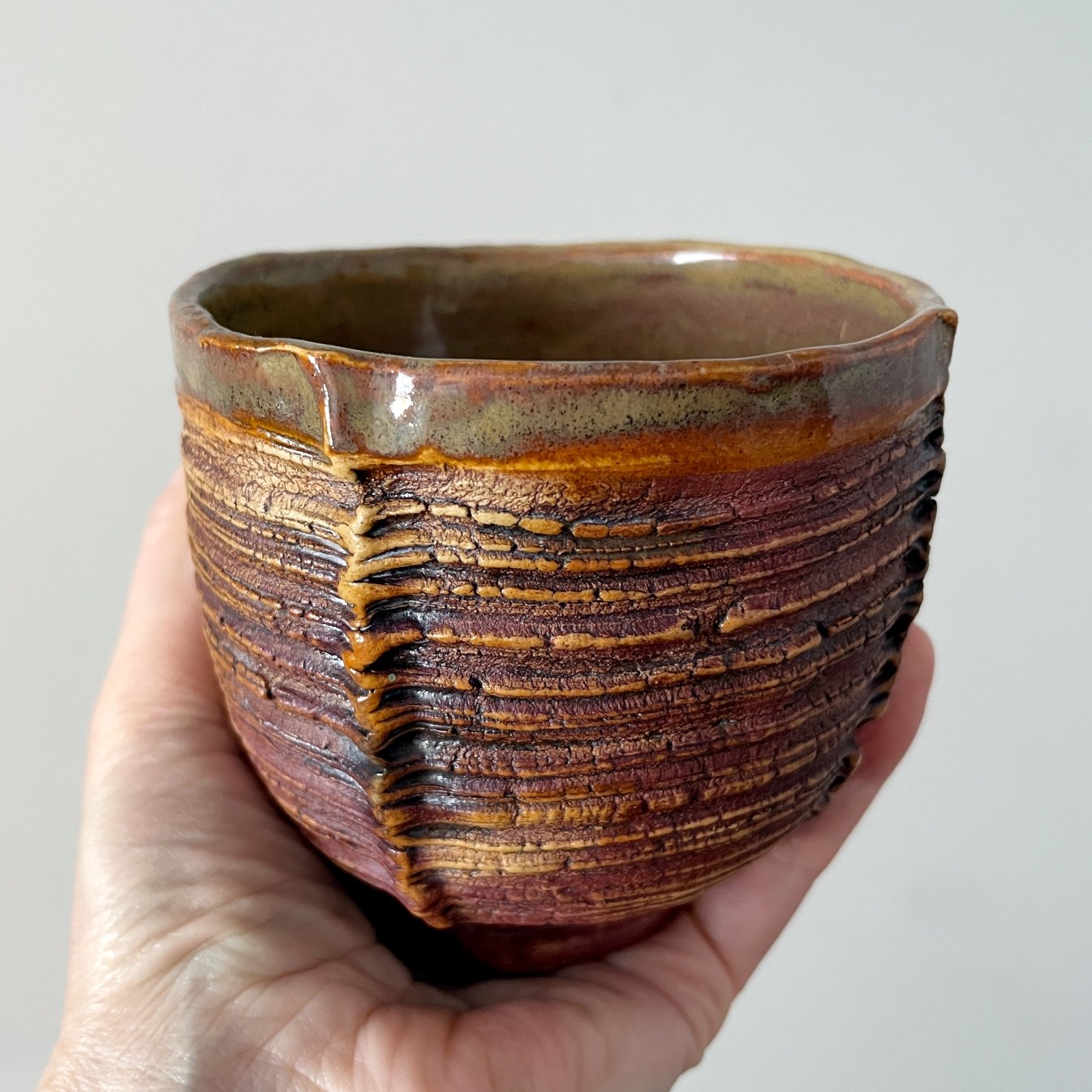 Handmade pottery tea cup held in hand for size reference