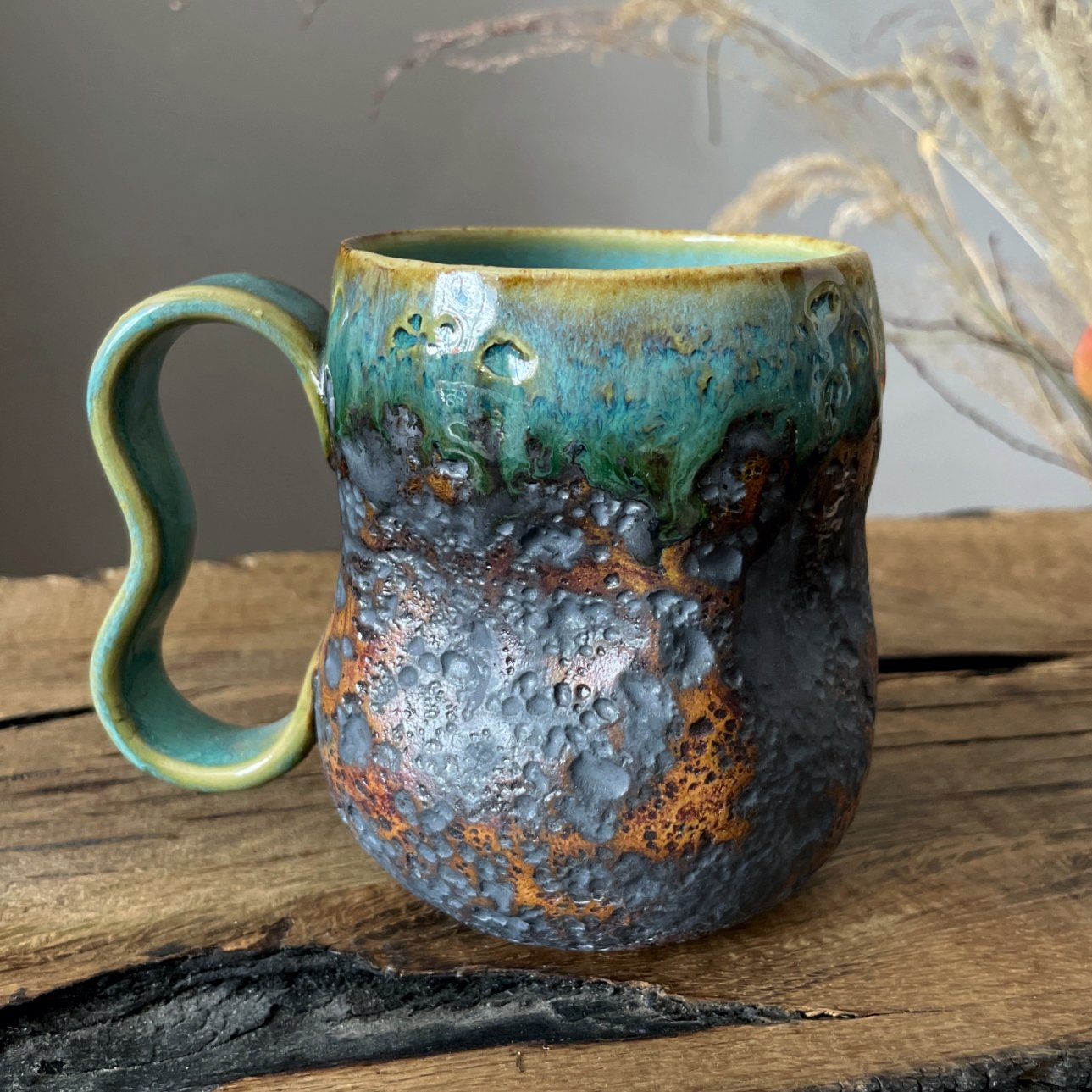 Handmade pottery mug with textured surface and sculptural handle